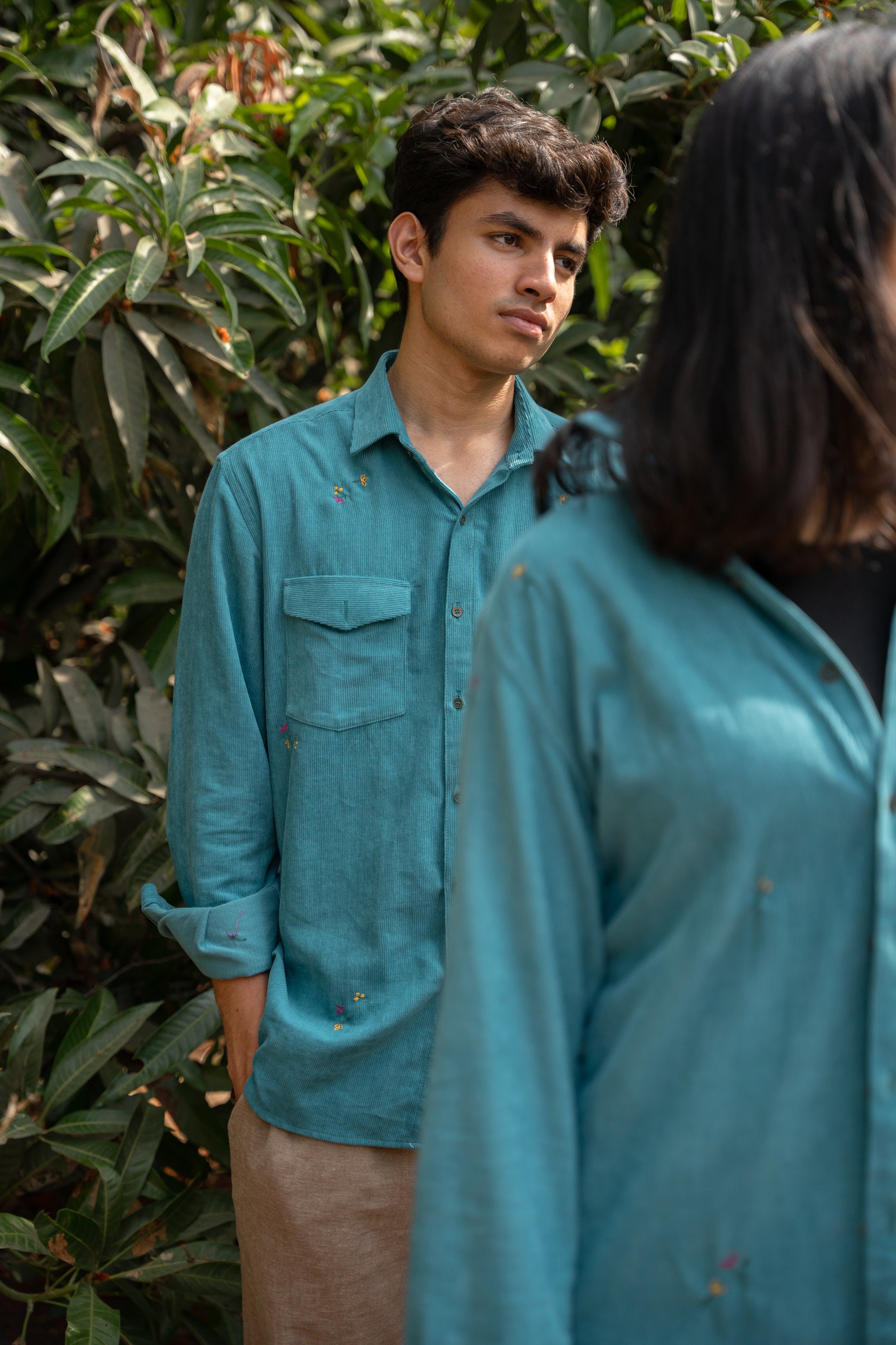 Soham in teal cotton corduroy teal overshirt is standing in front of trees