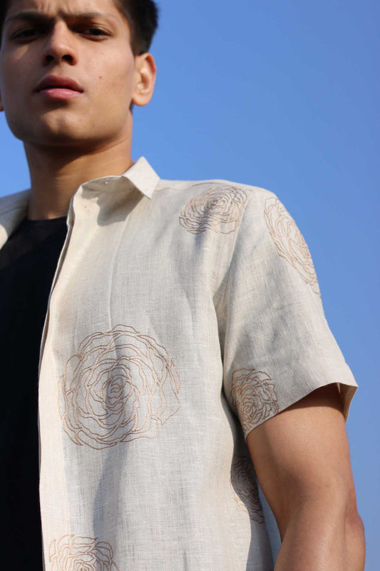 A man in a beige half-sleeve linen shirt with hand-embroidered roses in muted light brown color