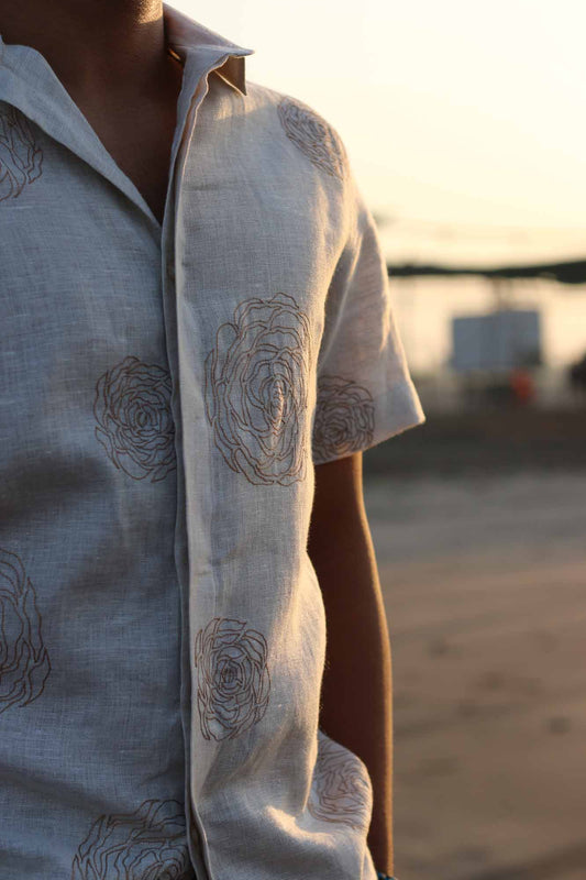 Details of a beige half-sleeve linen shirt with hand-embroidered roses in muted light brown color