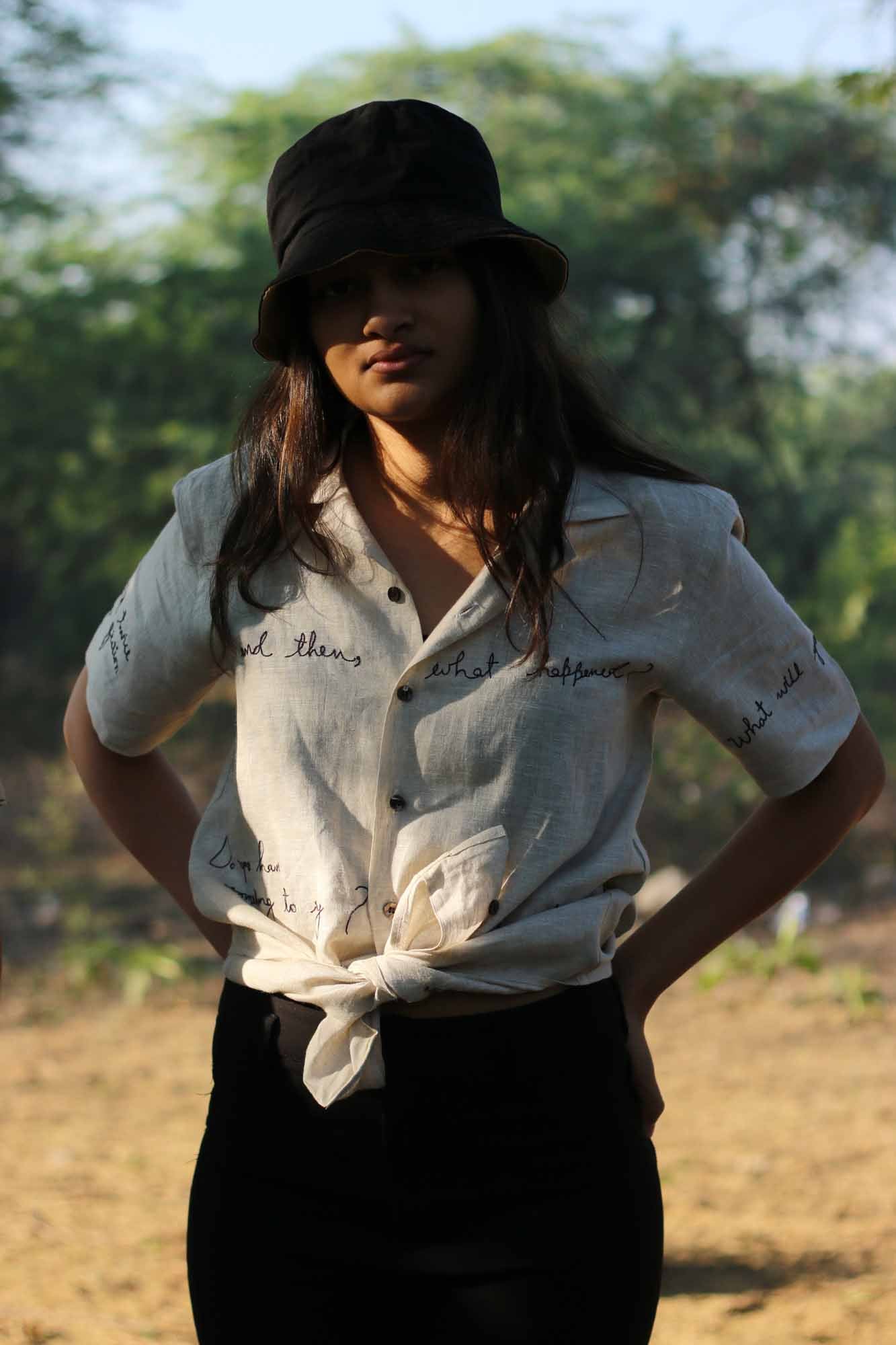 Preet in a beige linen shirt with embroidered texts is standing in the middle of a field