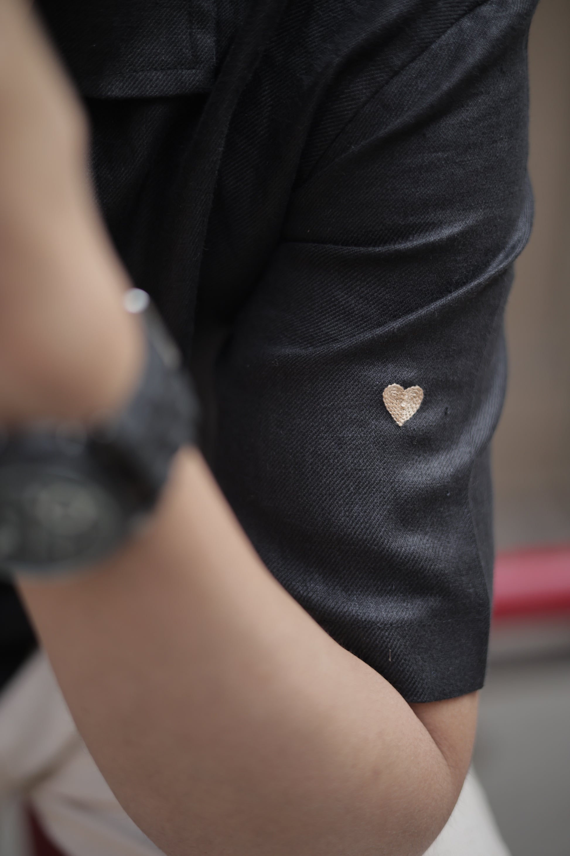 Details of a black linen half-sleeved shirt with tiny embroidered hearts