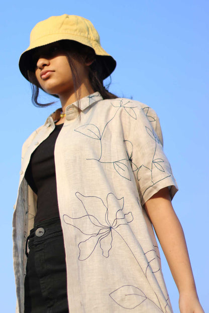 Side view of Manya in a beige hand-embroidered floral linen shirt