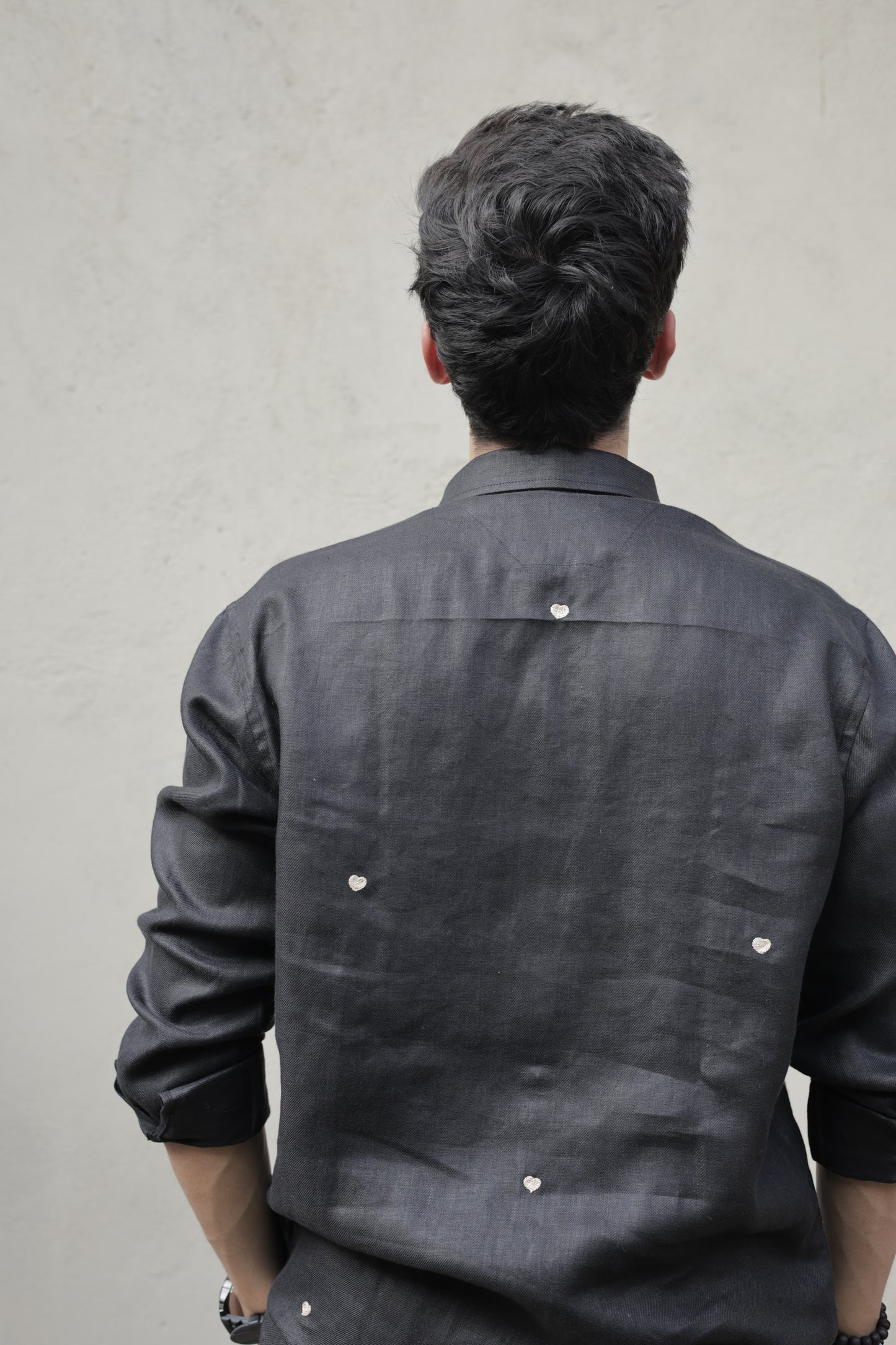 back details of a black linen full-sleeved shirt with tiny embroidered hearts