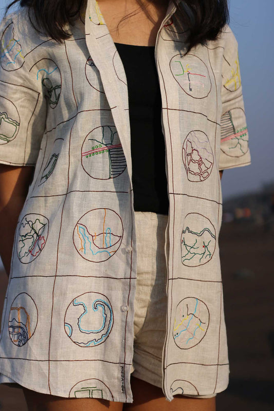 Details of a beige half-sleeved linen shirt with Hand-embroidered circular maps of cities