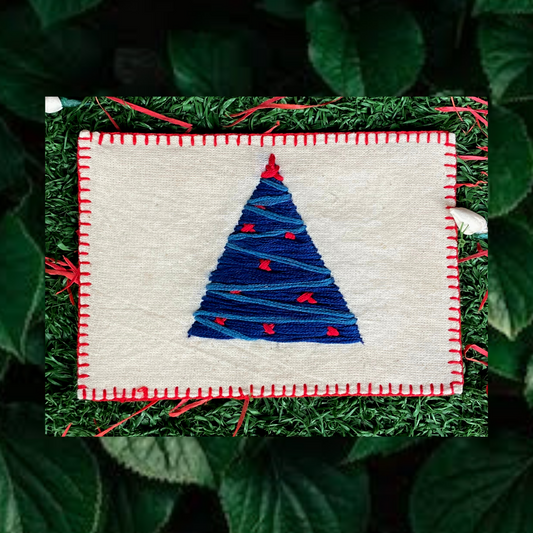 Close-up of intricate hand embroidery featuring a festive Christmas tree on a linen postcard.