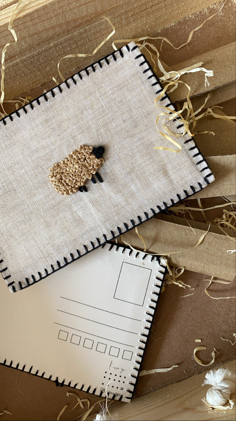 Hand-embroidered postcard featuring a unique black sheep on sustainable linen, ideal for those who celebrate individuality